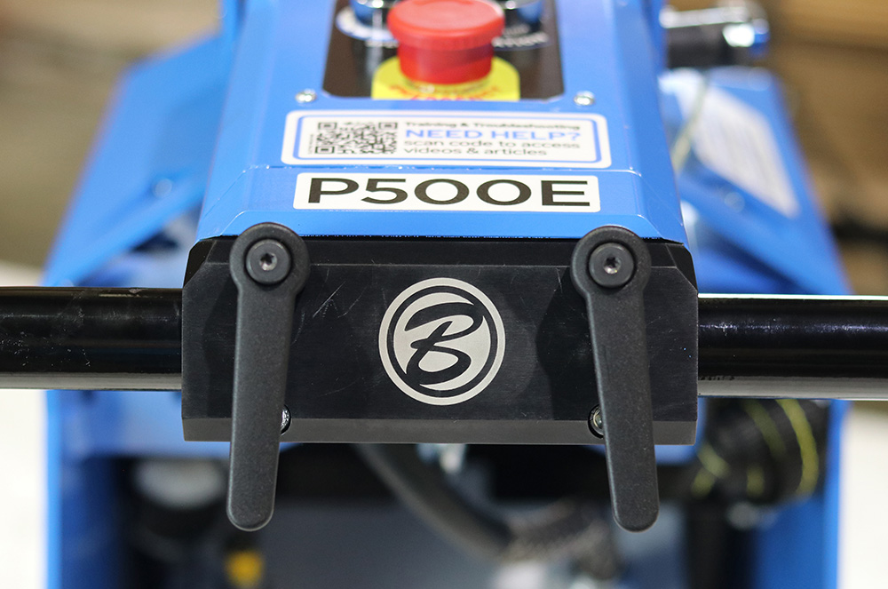 Close-up of a blue P500E hydraulic lift with two black handles and a circular logo on the front panel.