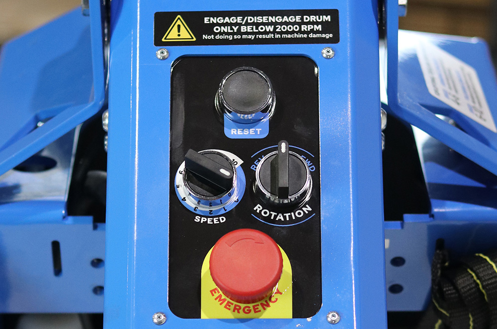 Blue industrial control panel with speed and rotation dials, a blue reset button, and a red emergency stop button.